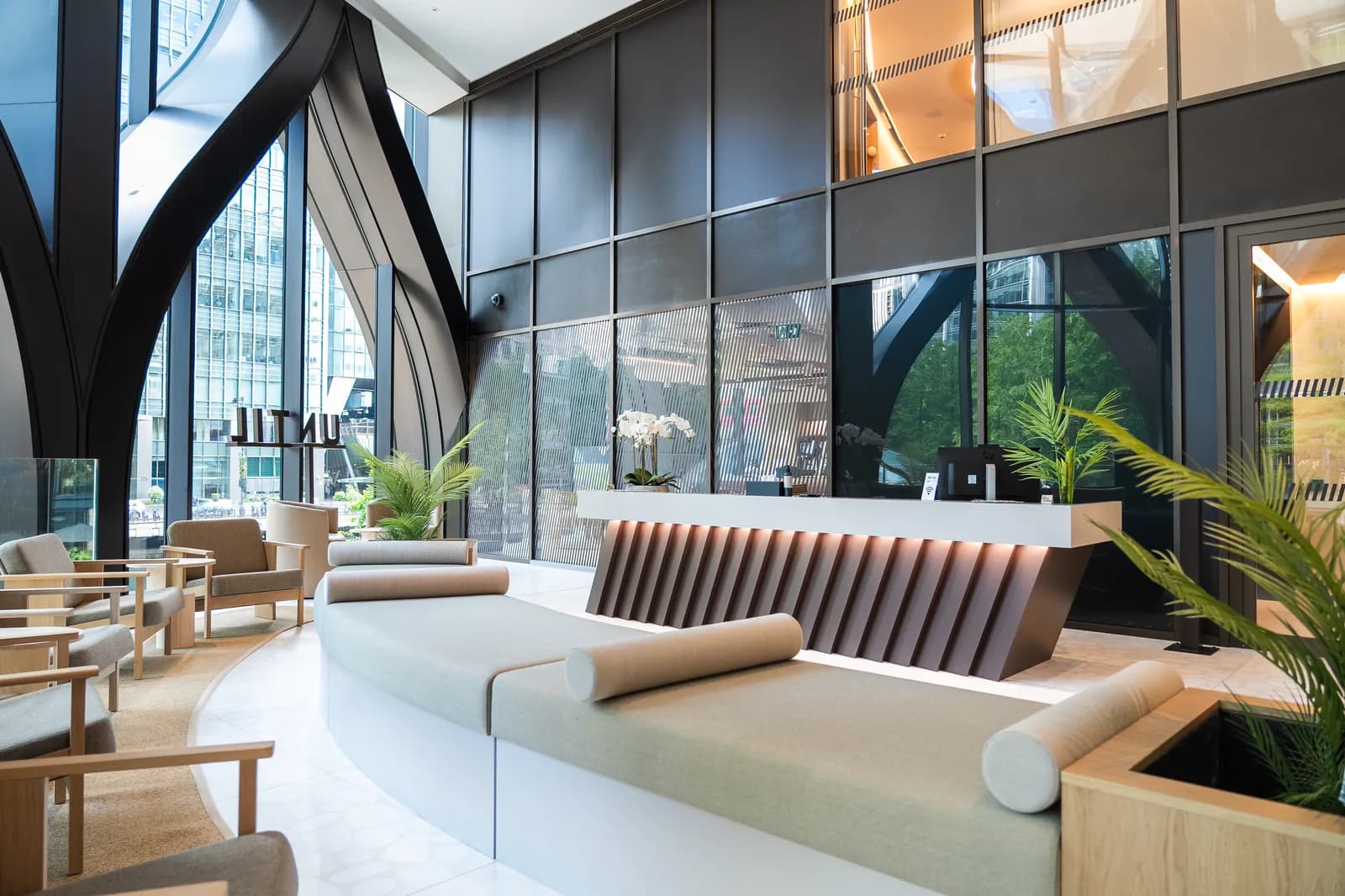 UNTIL Canary Wharf lobby and reception with curved sofa seating beneath cathedral-style glass arches.