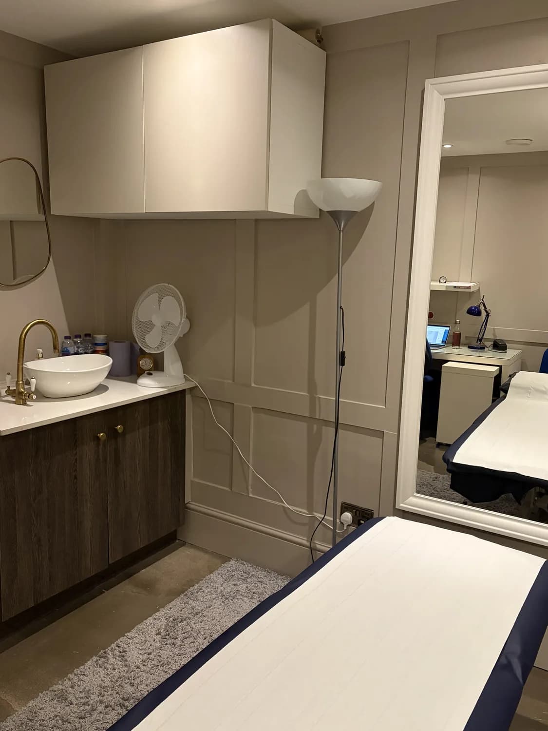 Treatment room at Atlas Osteopathy Moorgate with sink, full-length mirror and adjustable plinth.