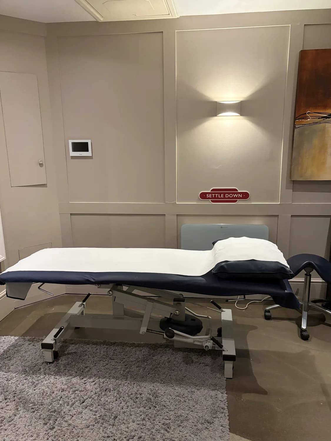 Panelled treatment room at Atlas Osteopathy Moorgate with adjustable plinth and warm ambient lighting.